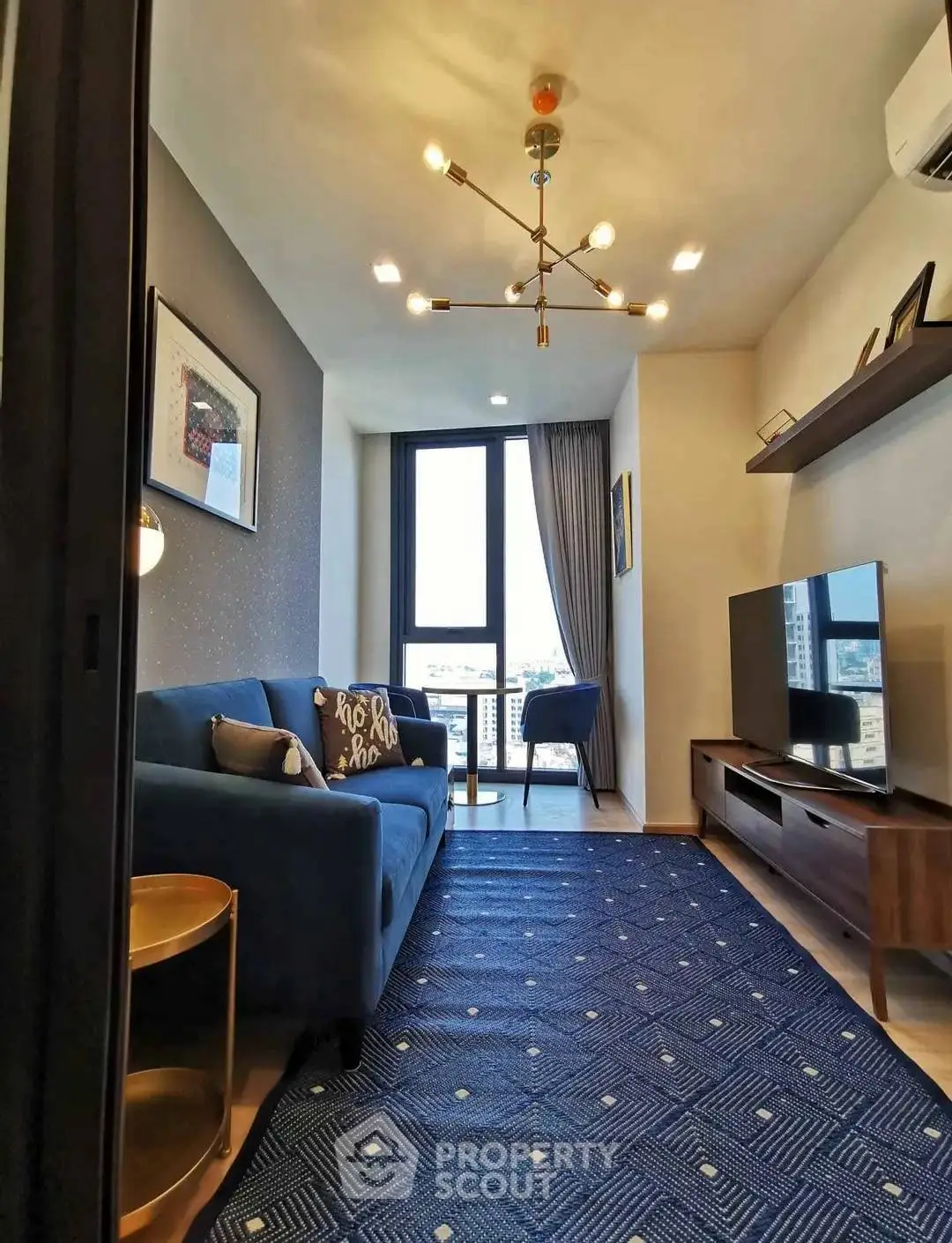 Modern living room with stylish decor and city view, featuring a blue sofa and elegant lighting.