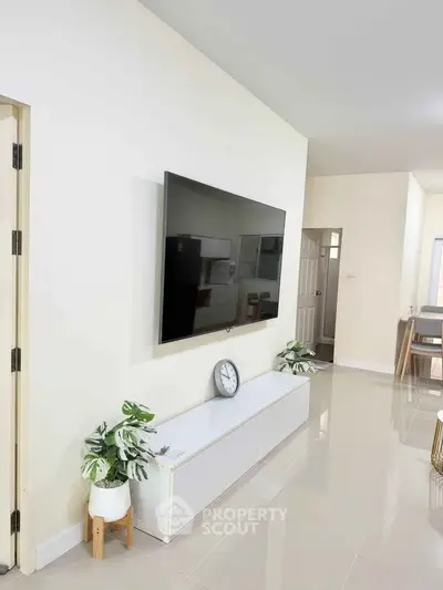 Modern living room with wall-mounted TV and sleek white furniture, perfect for contemporary living.