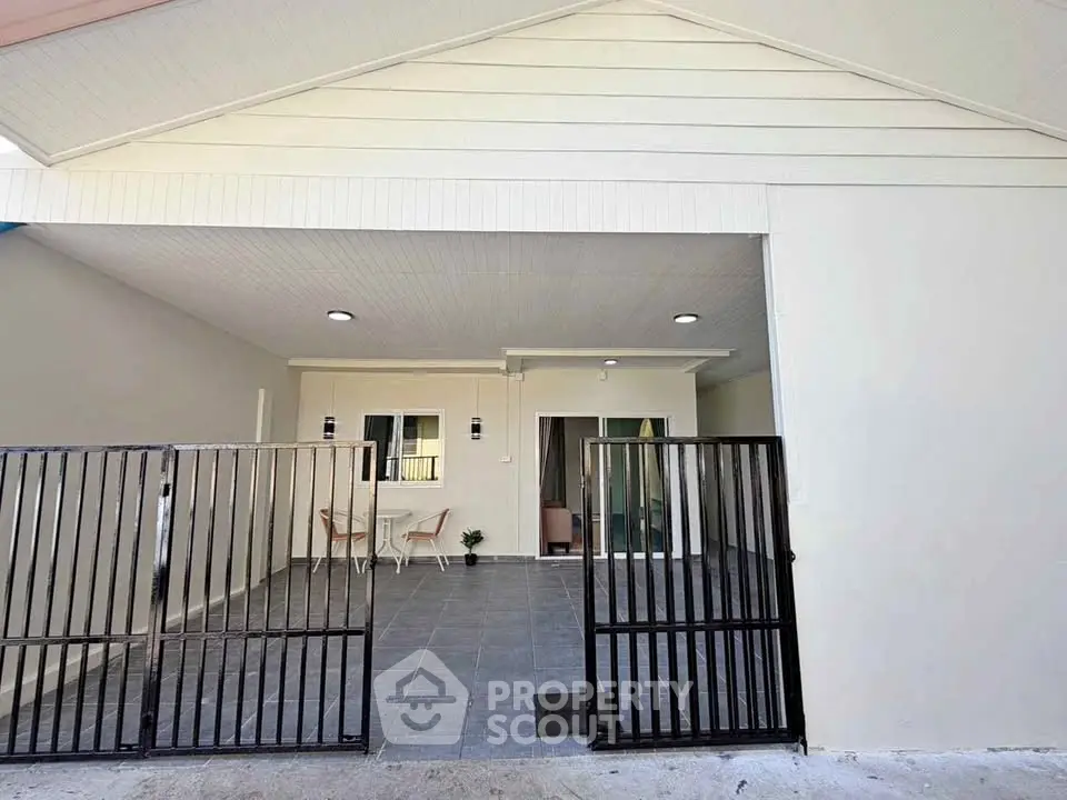 Modern house exterior with gated entrance and spacious patio area.