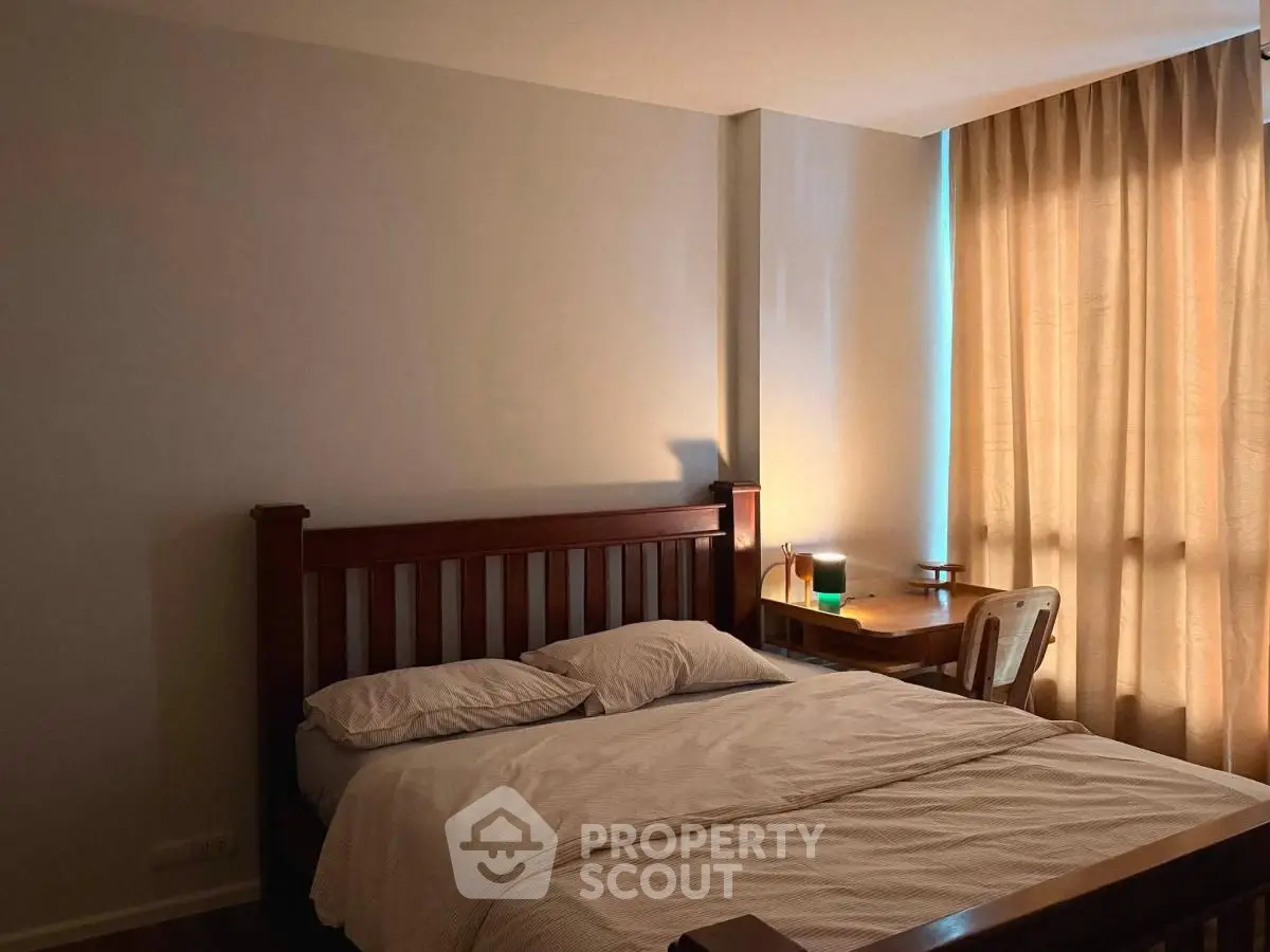 Cozy bedroom with wooden bed frame and natural light through curtains