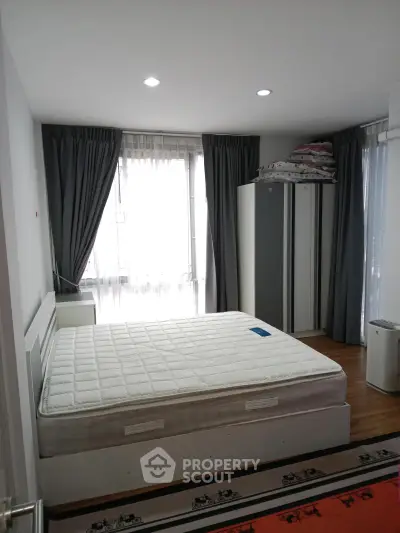 Spacious bedroom with large windows and modern furnishings in a stylish apartment.