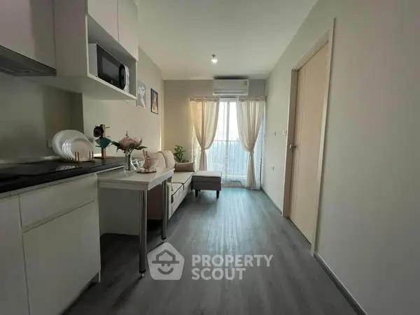 Modern apartment interior with sleek kitchen and cozy living area, featuring natural light and stylish decor.