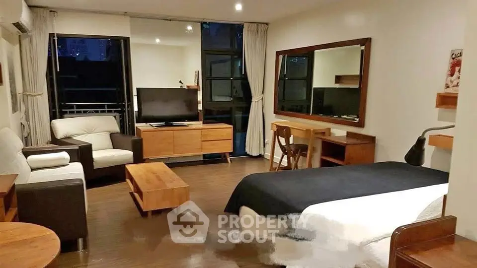 Spacious studio apartment with modern furniture and large windows for natural light.