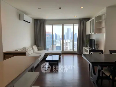 Spacious living room with city view, modern furniture, and large windows in a high-rise apartment.