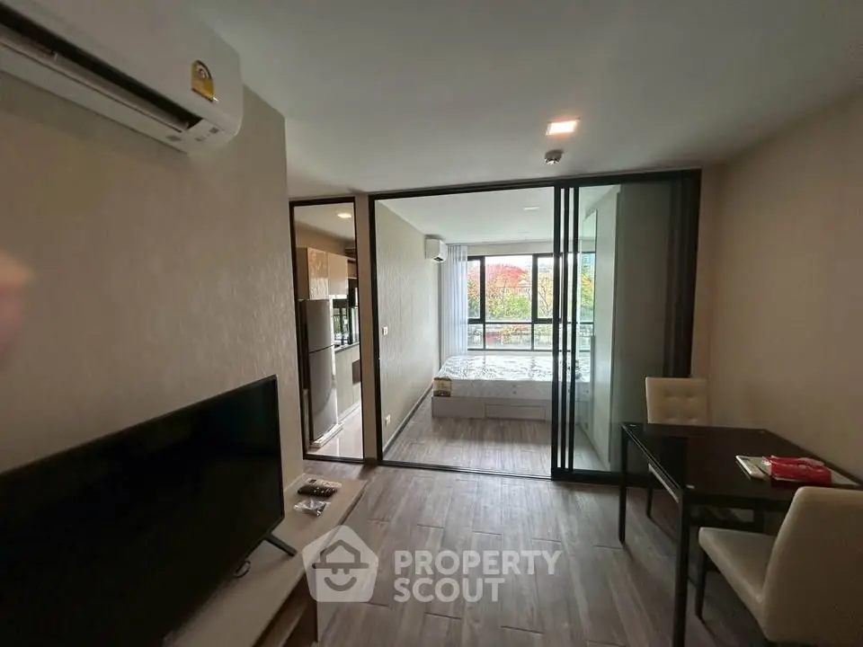 Modern apartment interior with open layout, featuring a cozy living area and bedroom with large windows.