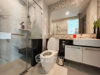 Modern bathroom with glass shower, sleek vanity, and elegant tile design.