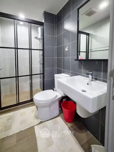 Modern bathroom with sleek black tiles and glass shower enclosure