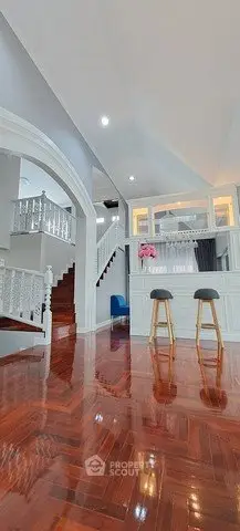 Elegant open-plan living area with polished wooden floors and stylish bar stools