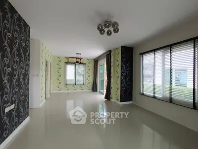 Spacious living room with elegant wallpaper and large windows for natural light.