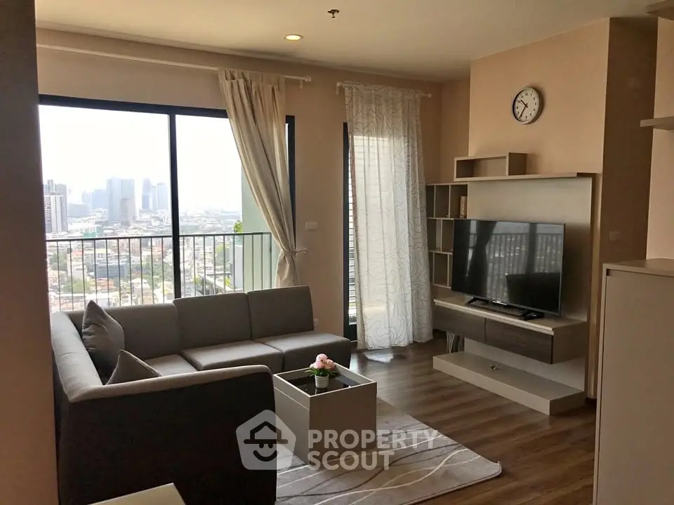 Modern living room with city view, featuring stylish furniture and large windows for natural light.
