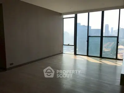 Spacious modern living room with floor-to-ceiling windows and city view.