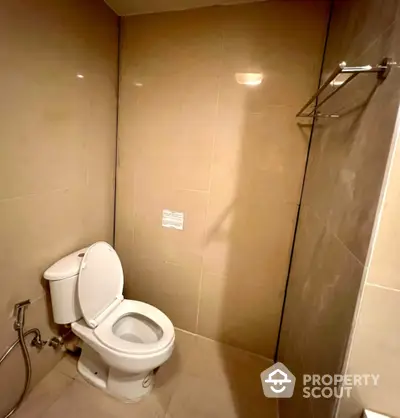 Modern bathroom with sleek beige tiles and white toilet in a minimalist design.