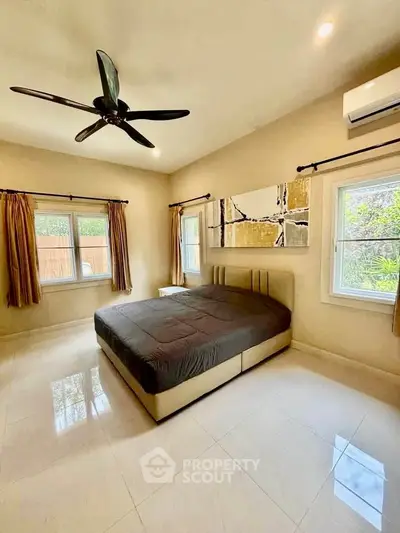 Spacious bedroom with modern decor and large windows offering natural light.