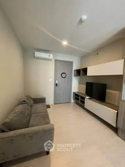 Modern living room with sleek furniture and wall-mounted TV in a cozy apartment.