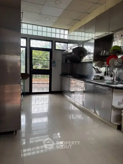 Spacious modern kitchen with stainless steel appliances and large windows offering natural light.