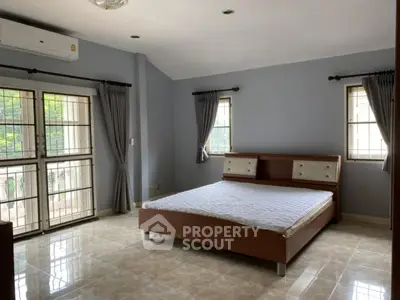 Spacious bedroom with large windows and modern decor in a serene home.
