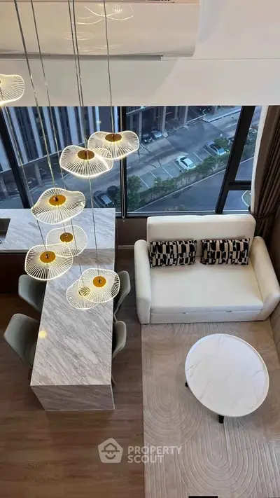 Modern living room with stylish lighting and city view from large windows.