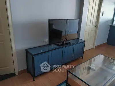 Modern living room with sleek TV stand and glass coffee table on wooden flooring.