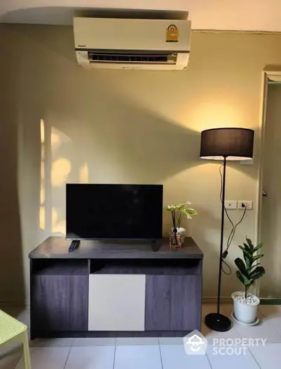 Cozy living room with modern TV stand, air conditioning, and stylish floor lamp.