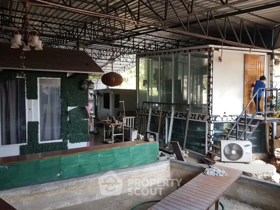 Unique industrial-style home with metal framework and glass walls, featuring an outdoor area with potential for customization.