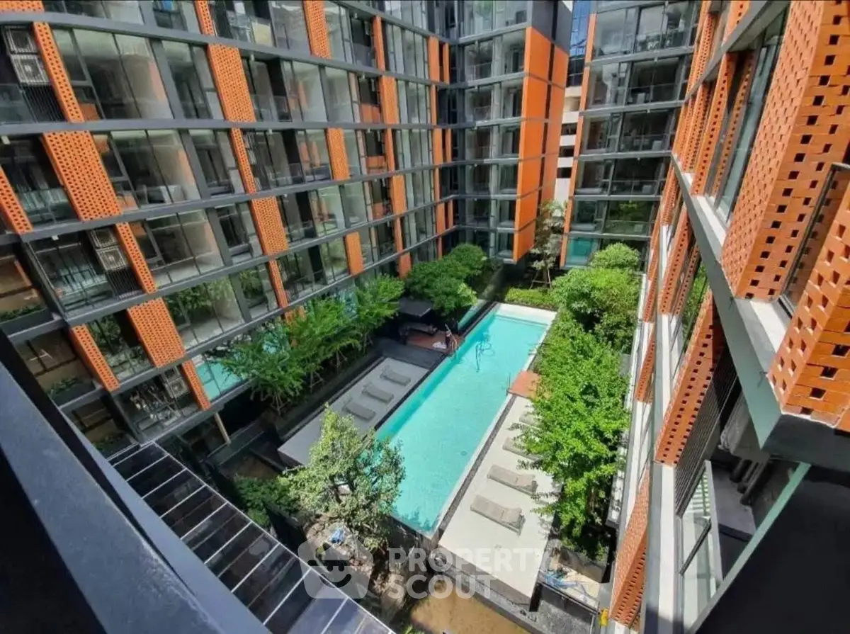 Modern apartment complex with central pool and lush greenery