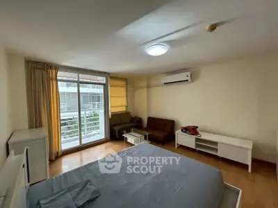 Spacious bedroom with modern furnishings and large window offering natural light.