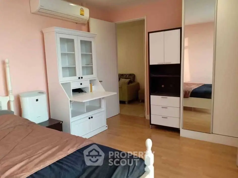 Spacious bedroom with modern furniture and mirrored wardrobe in a cozy apartment.
