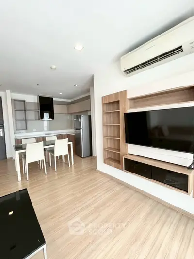 Modern living room with open kitchen, featuring sleek furniture and built-in TV unit.