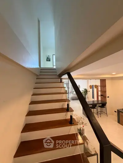 Modern staircase leading to a bright open-plan living area with stylish decor.