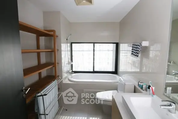 Modern bathroom with bathtub and sleek fixtures, featuring natural light from large window.