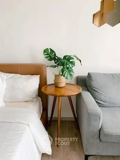 Stylish bedroom corner with cozy bed, modern sofa, and chic wooden side table.