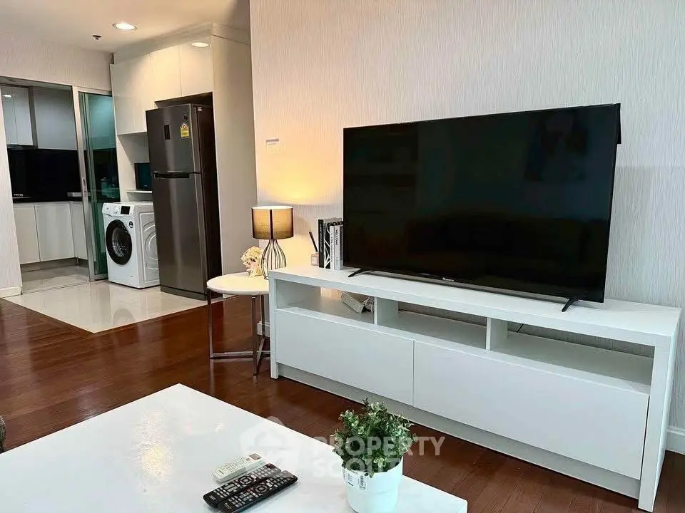 Modern living room with TV, washing machine, and sleek kitchen area.