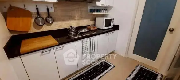 Modern kitchen with sleek cabinetry and microwave, featuring a stylish backsplash.