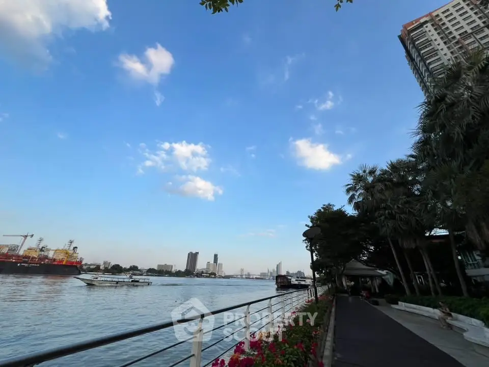 Stunning riverside view with lush greenery and modern high-rise building, perfect for urban living.