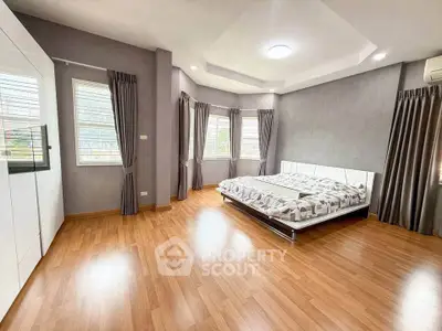 Spacious modern bedroom with hardwood floors and large windows for natural light.