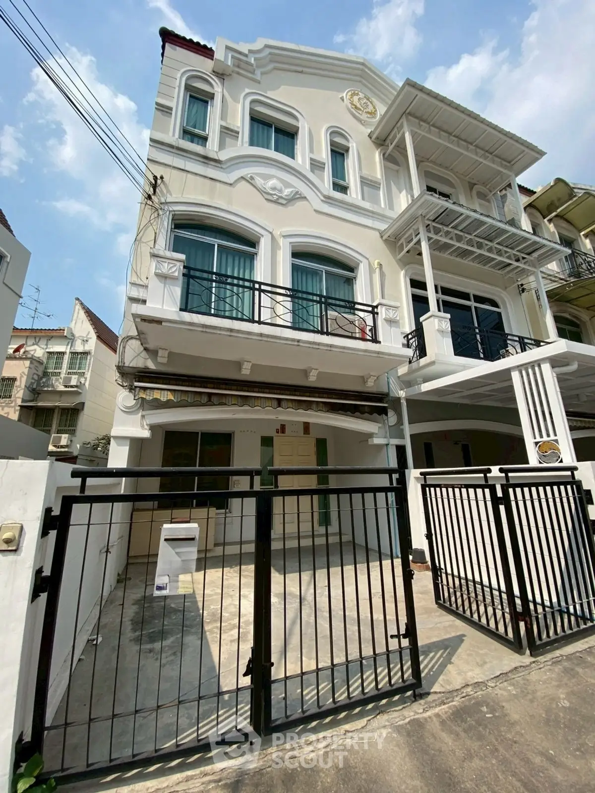 Charming three-story townhouse with gated entrance and elegant facade in a serene neighborhood.