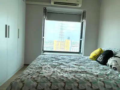 Cozy bedroom with large window offering city view, featuring modern decor and ample storage space.