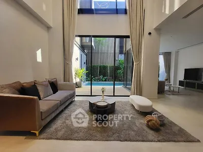 Luxurious living room with pool view, modern furniture, and high ceilings in a contemporary home.