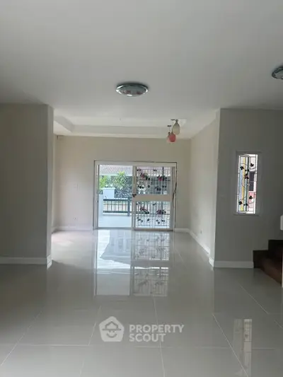 Spacious modern living room with glossy tile flooring and large windows for natural light.