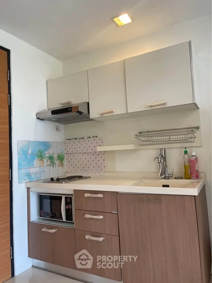 Modern compact kitchen with sleek cabinetry and built-in appliances in a stylish apartment.