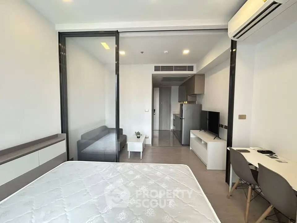 Modern studio apartment with open layout, featuring a cozy living area and sleek kitchen.