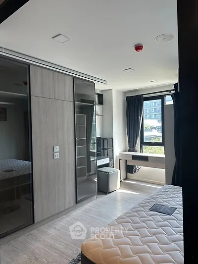 Modern bedroom with large window and built-in wardrobe in a stylish apartment.