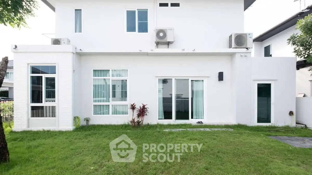 Modern white house exterior with lush green lawn and large windows