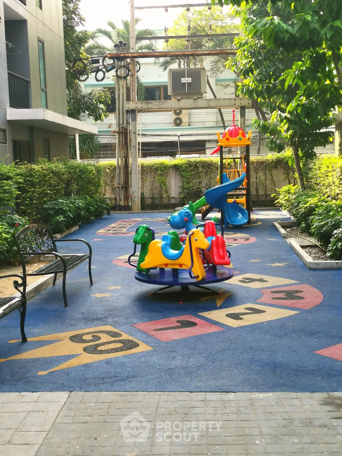 Charming outdoor playground area in residential complex with colorful play equipment and lush greenery.