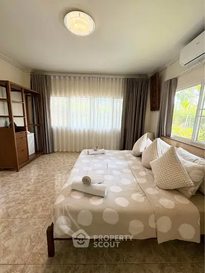 Spacious bedroom with large windows and elegant decor, perfect for relaxation and comfort.