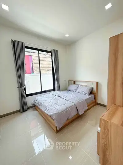 Bright and cozy bedroom with large window and modern furnishings