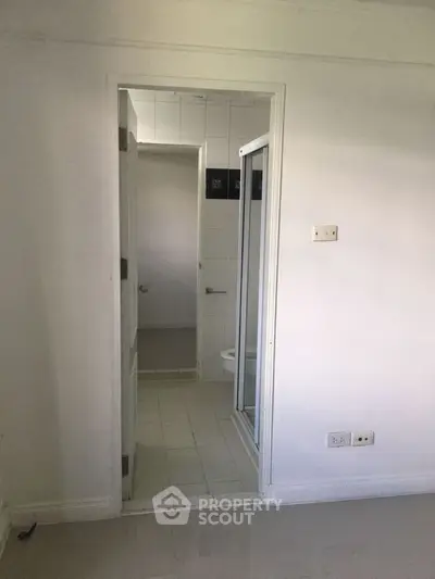 Minimalist bathroom entrance with white tiles and modern fixtures.