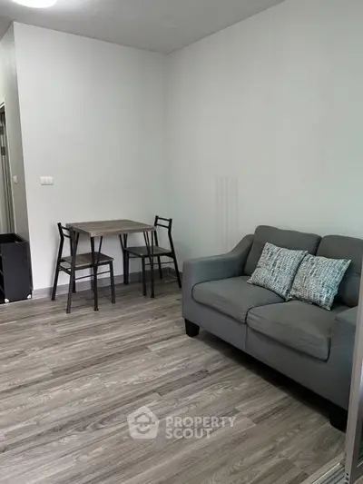 Cozy living room with modern gray sofa and dining table in a stylish apartment.