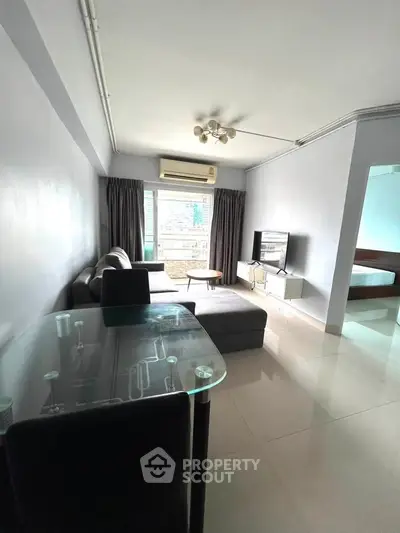 Modern living room with sleek furniture and large window offering city views.