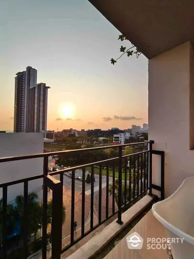 Stunning balcony view with sunset over city skyline and modern high-rise buildings.